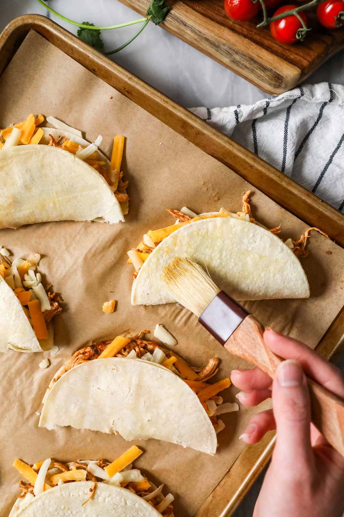 Brush the chicken tacos with oil before baking.