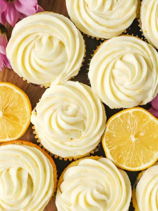 Overhead view of cupcakes frosted with lemon cream cheese frosting among lemon halves.