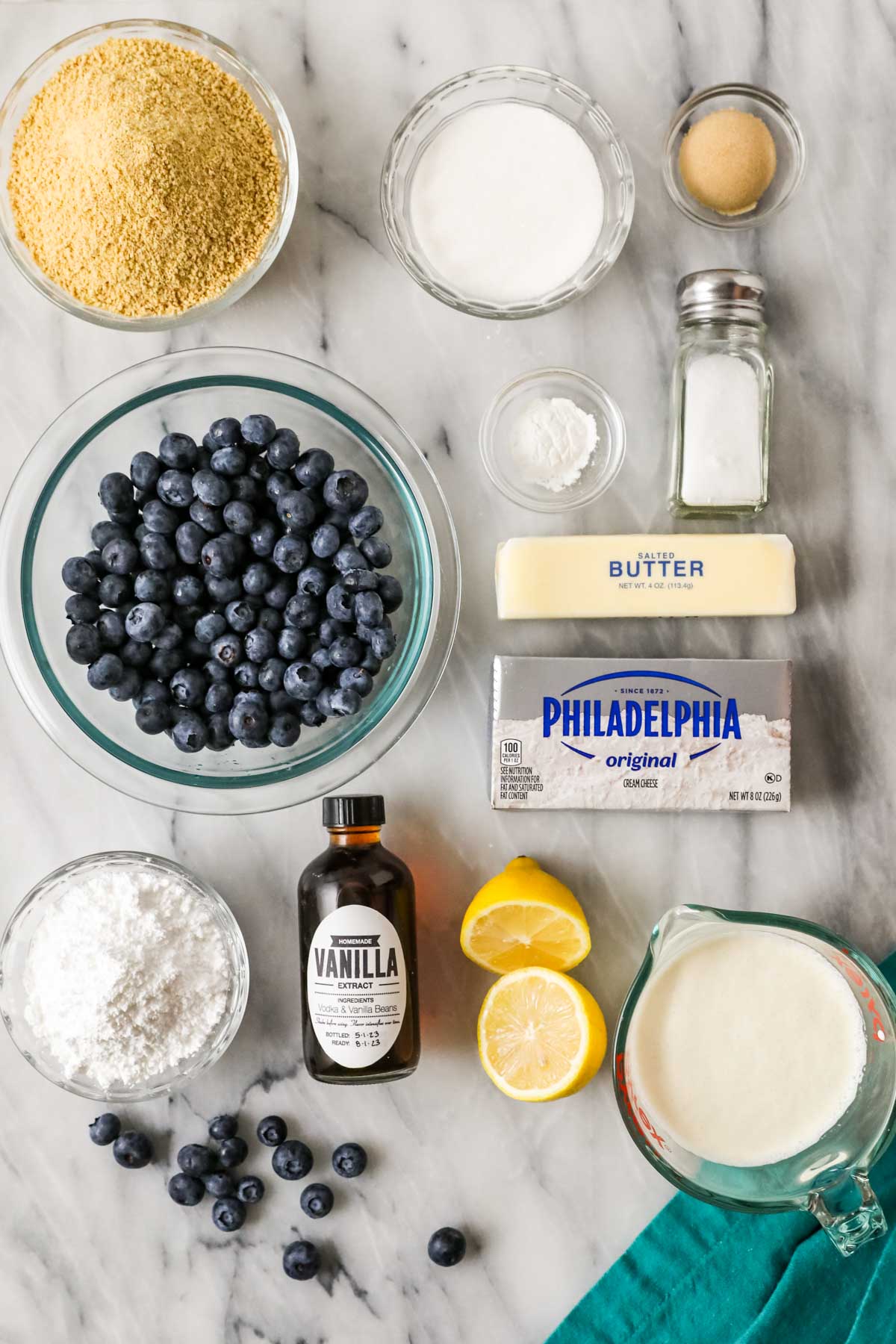 Overhead view of ingredients including graham cracker crumbs, blueberries, cream cheese, and more.