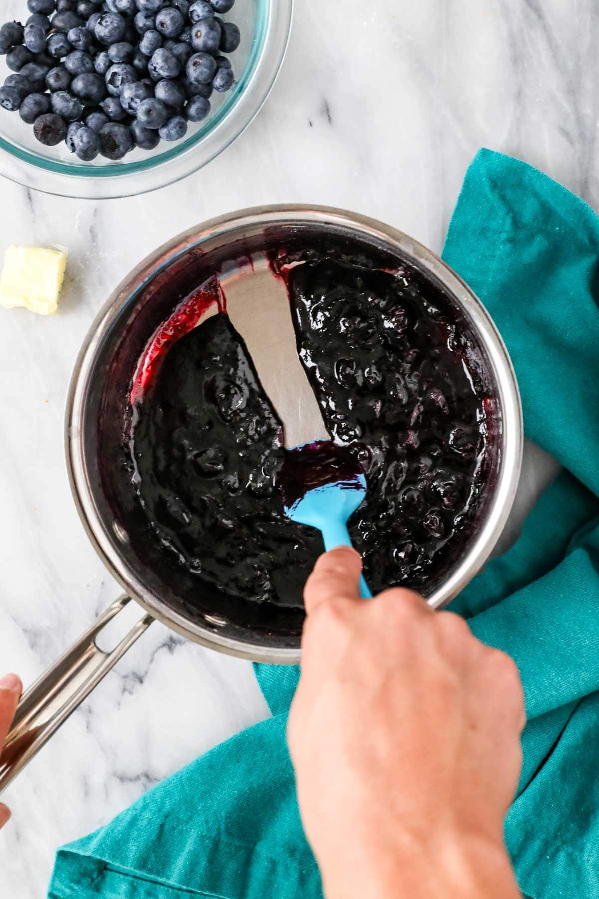 Spatula dragging through a cooked blueberry mixture to show that it has thickened properly.
