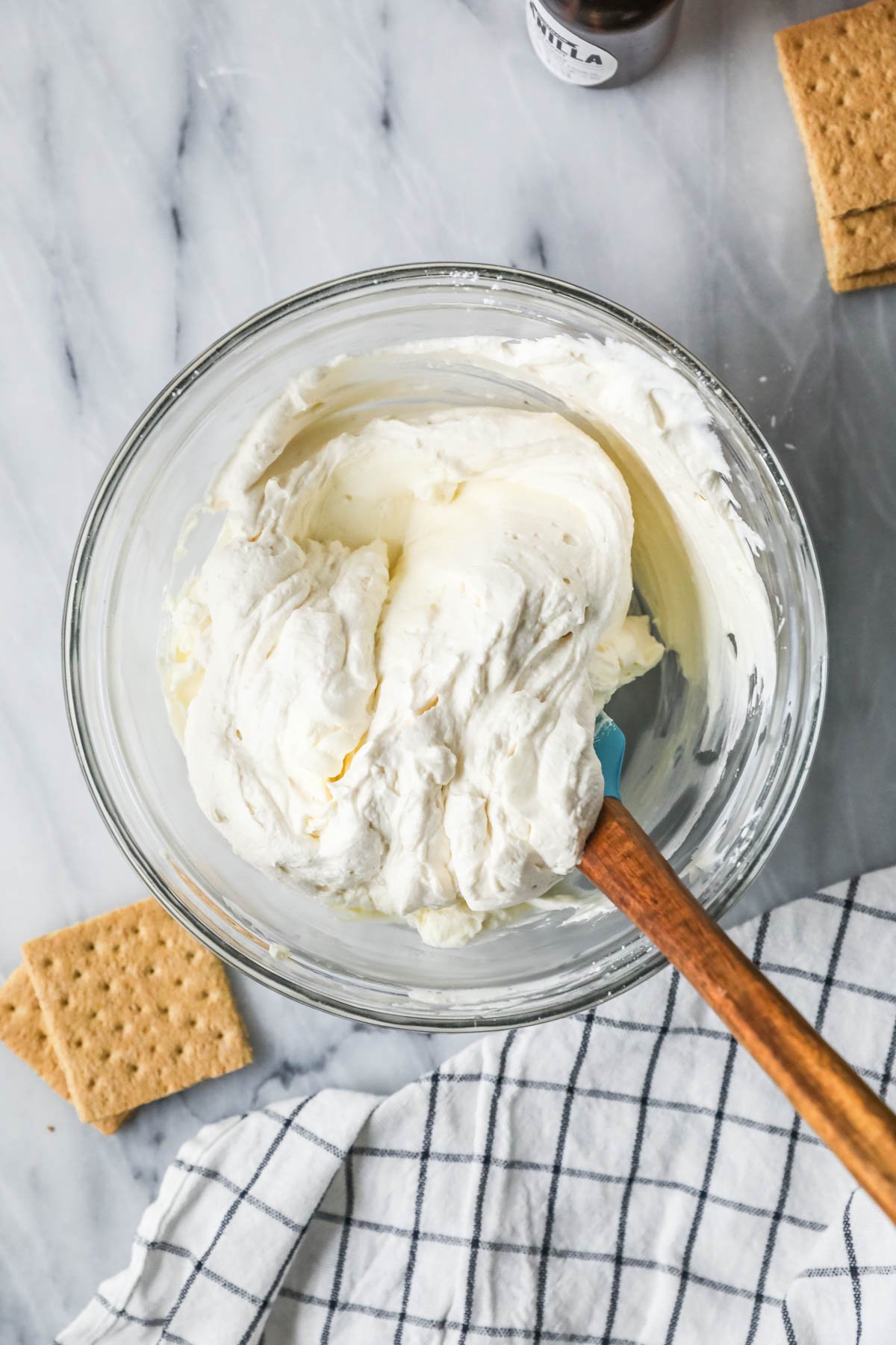 Overhead view of heavy cream being folded into a cream cheese mixture.