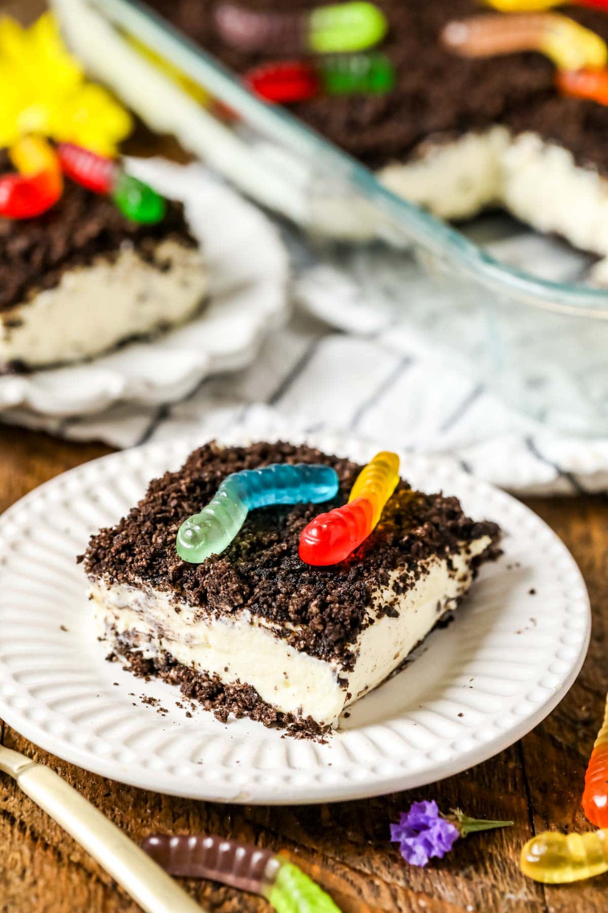 Slice of dirt cake topped with colorful gummy worms.