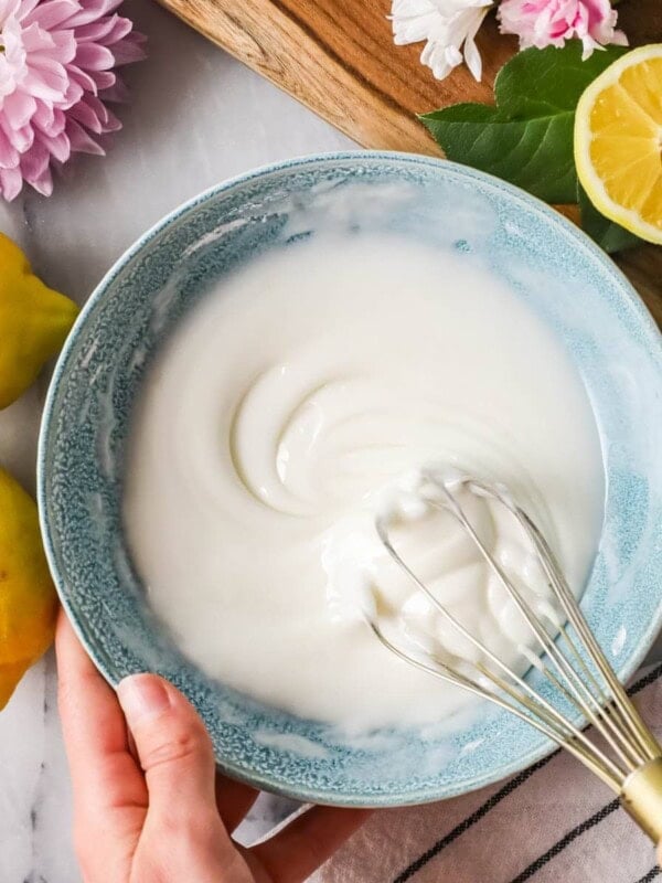 Overhead view of a bowl of lemon glaze being whisked.