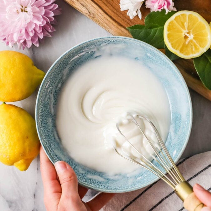 Overhead view of a bowl of lemon glaze being whisked.