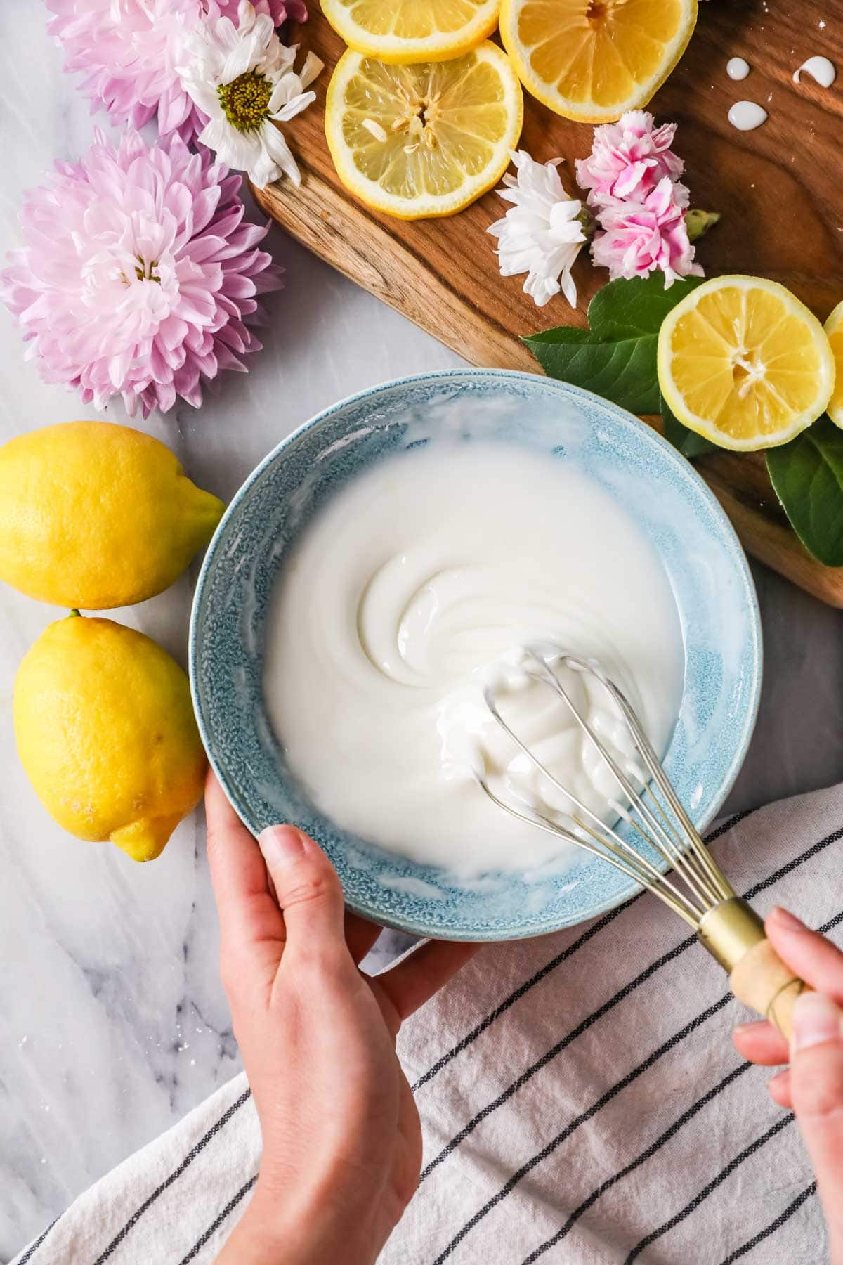 Overhead view of a bowl of lemon glaze being whisked.