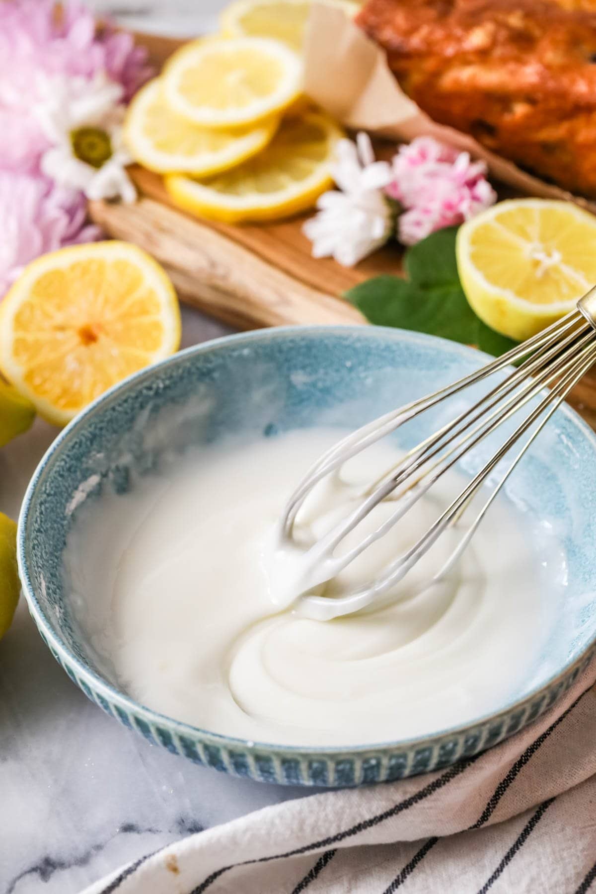 Whisk lifting out of a bowl of glaze made from lemon juice and powdered sugar.