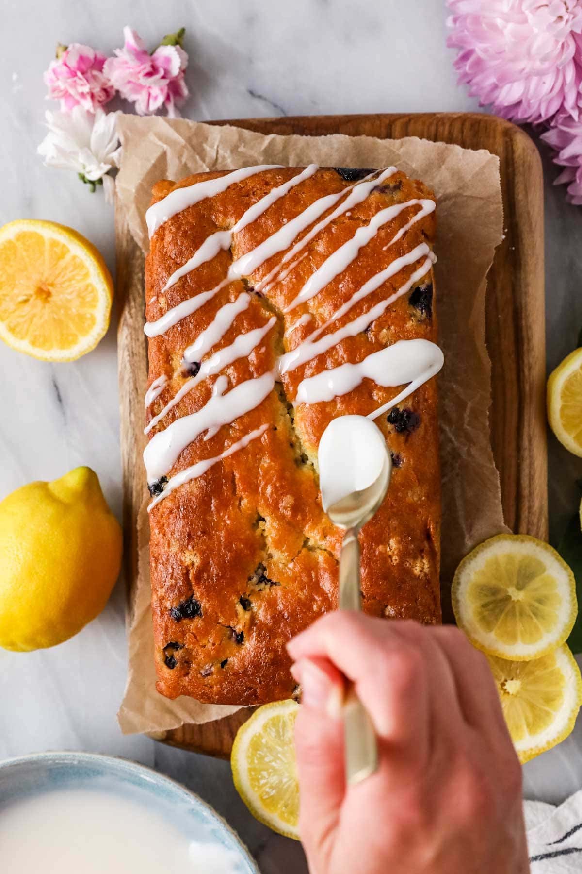 Overhead view of lemon glaze being drizzled over a loaf of bread.