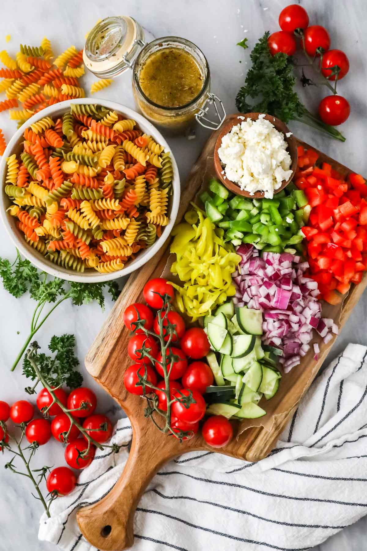 Elevated landscape with ingredients including tricolor lamb pasta, tomatoes, cucumbers, etc.