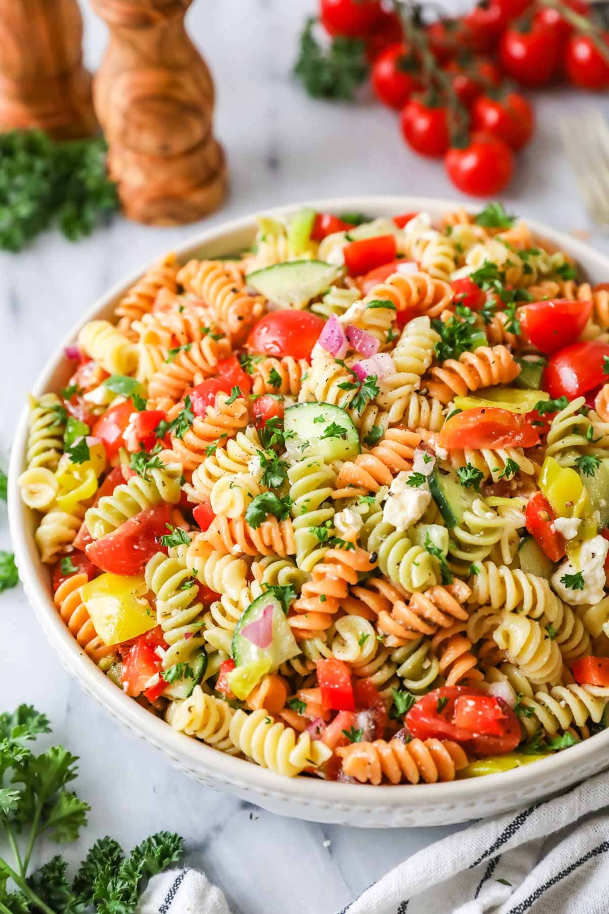A bowl of pasta salad made of tricolor wool, vegetables and feta cheese.