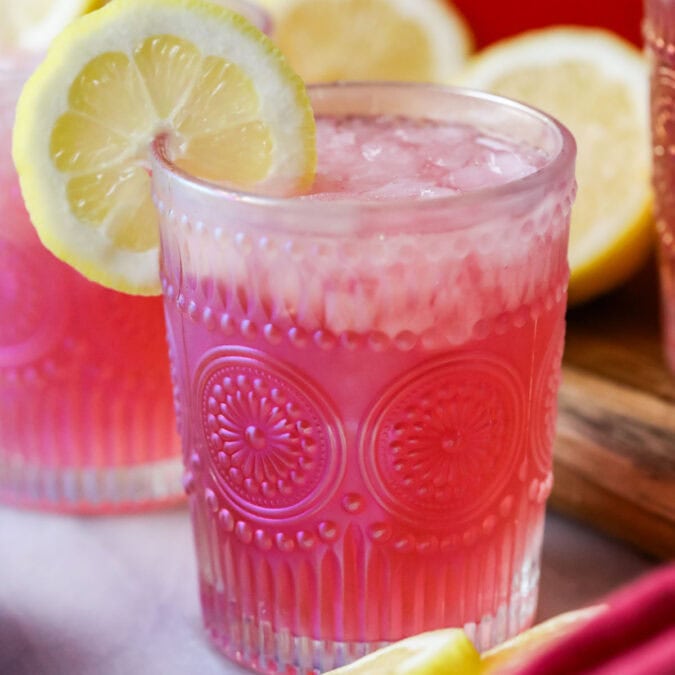 Glass of pink lemonade garnished with a lemon slice.