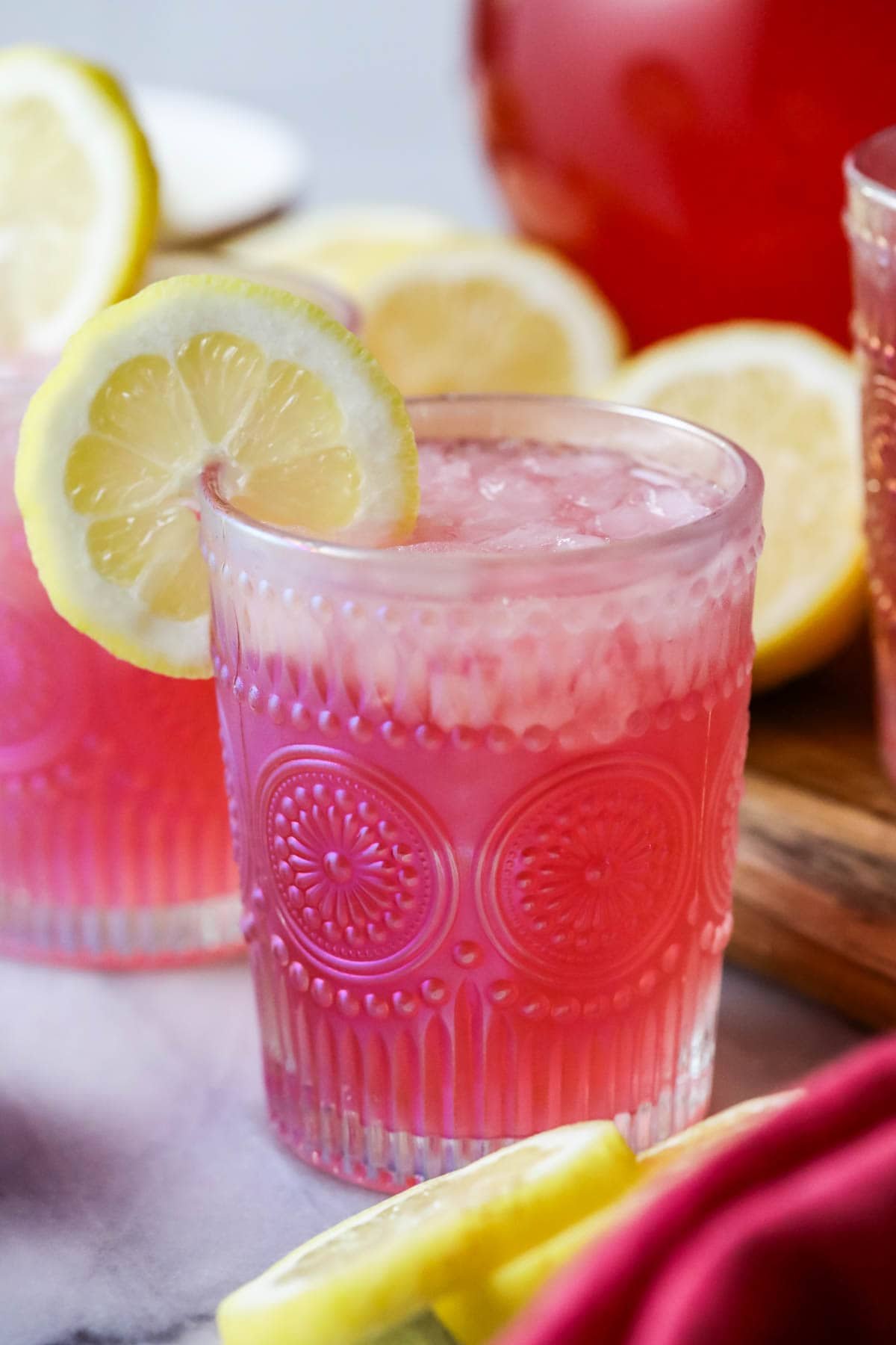 A cup of pink lemonade is decorated with lemon slices.