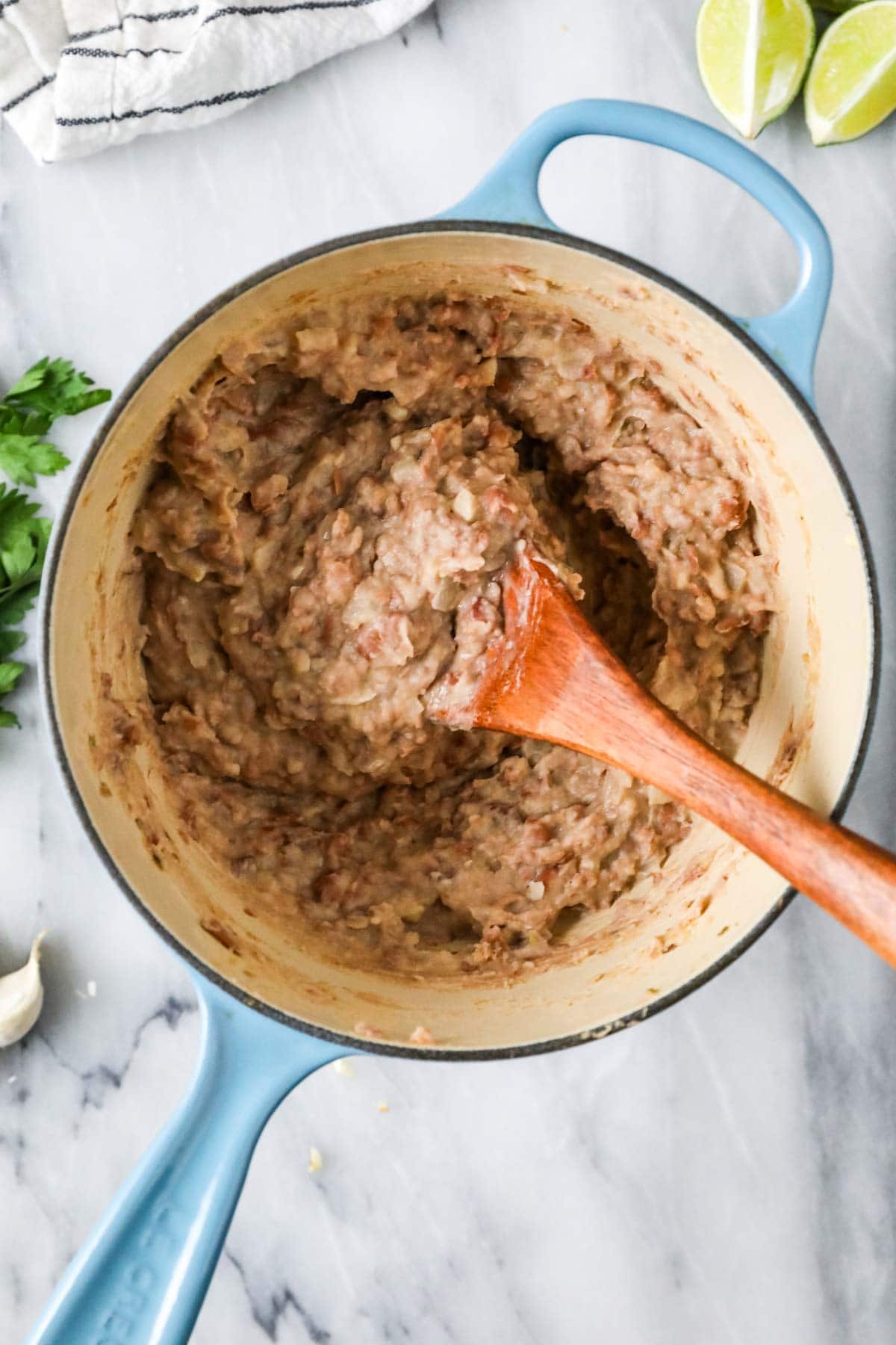Spoon stirring refried beans in a dutch oven.