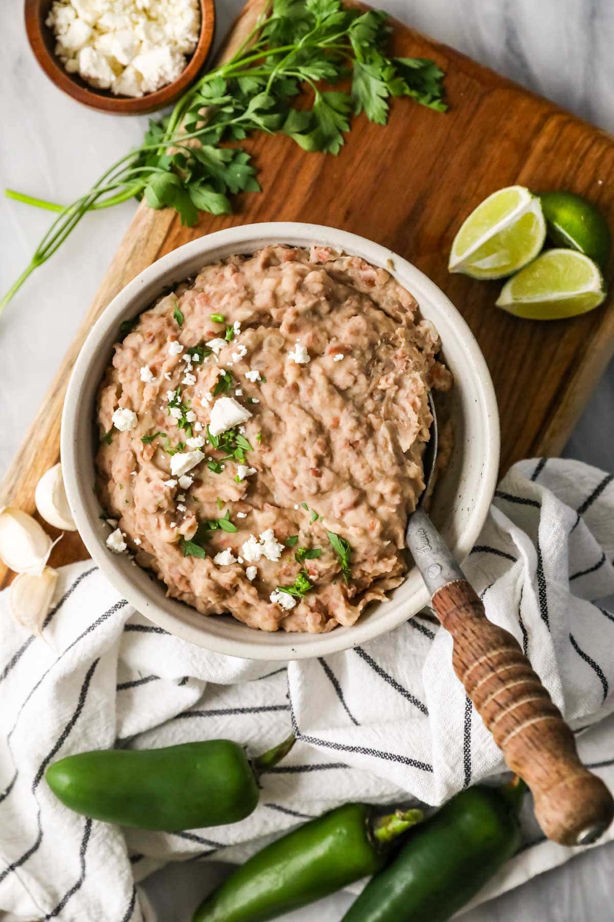 Overhead view of a bowl of refried beans topped with cilantro and cheese.