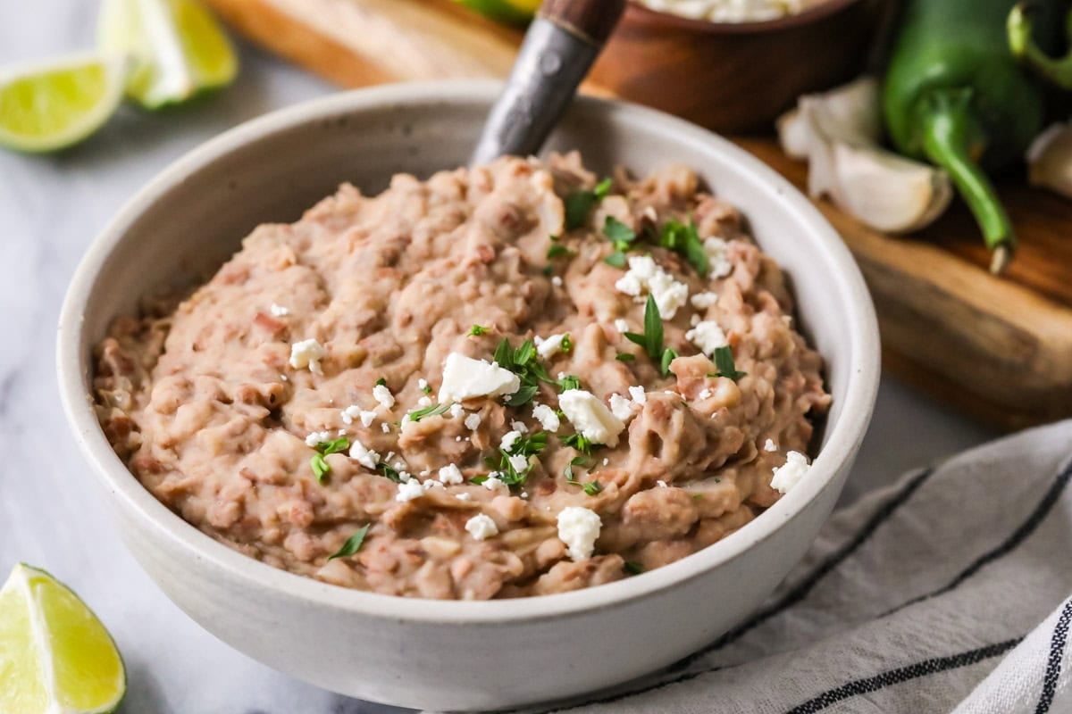 Bowl of pinto beans that have been mashed with spices and onion.