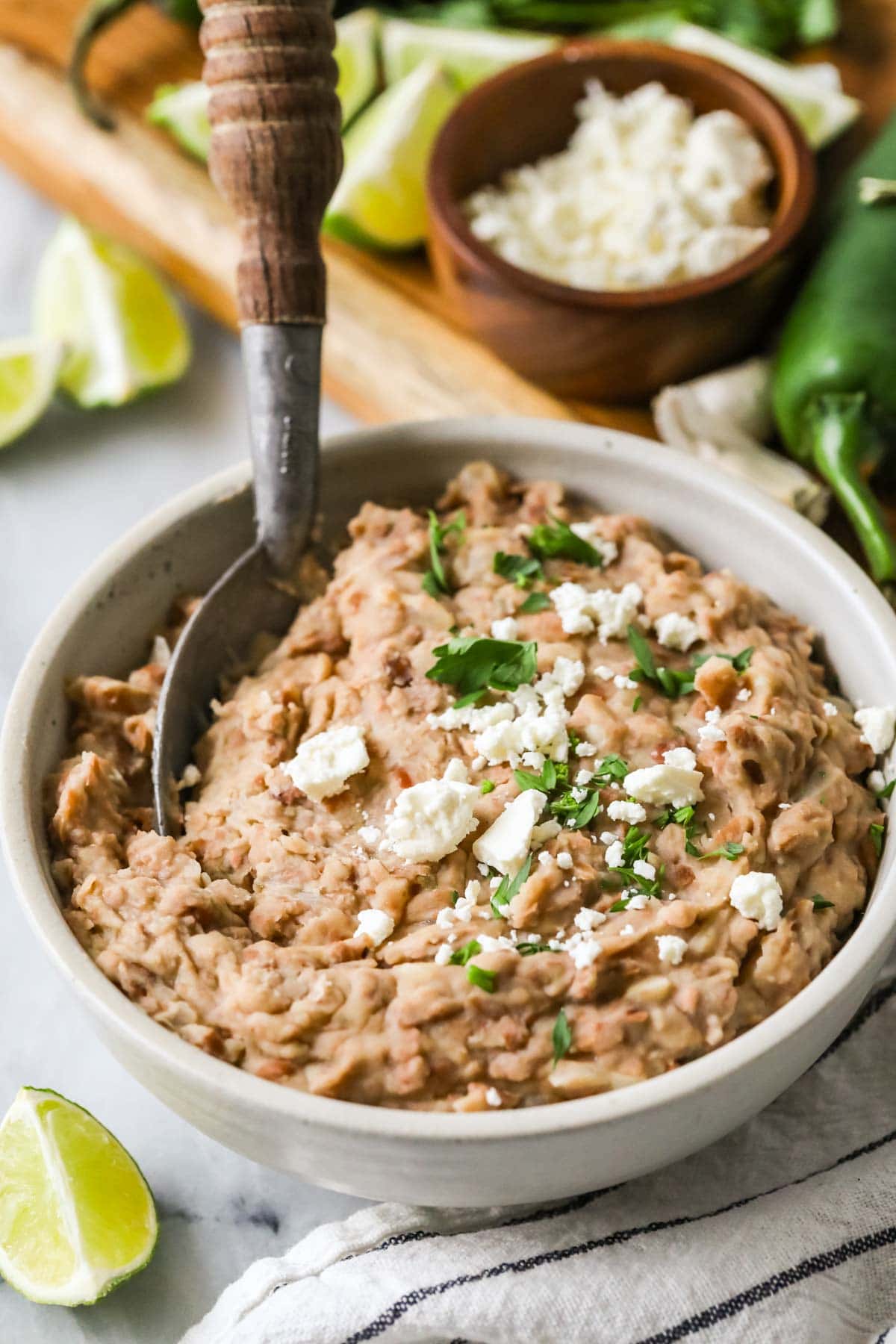 Bowl of homemade refried beans topped with cheese and cilantro.