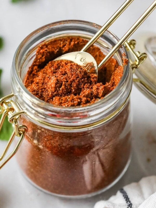 Teaspoon scooping from a jar of taco seasoning made from a homemade taco seasoning recipe.
