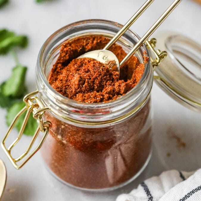 Teaspoon scooping from a jar of taco seasoning made from a homemade taco seasoning recipe.
