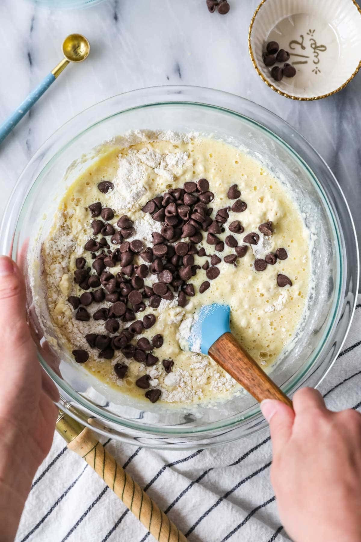 Overhead view of a bowl of pancake batter with chocolate chips being folded in.