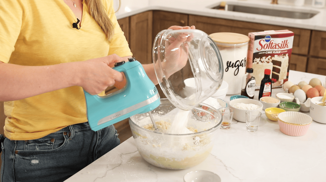 Dry ingredients being poured into a butter and sugar mixture to create a cookie dough.
