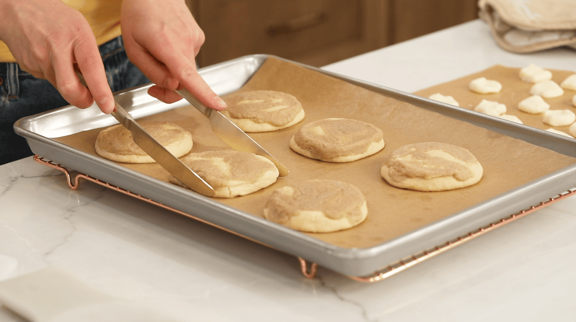 Squaring cookies using a pair of knives.