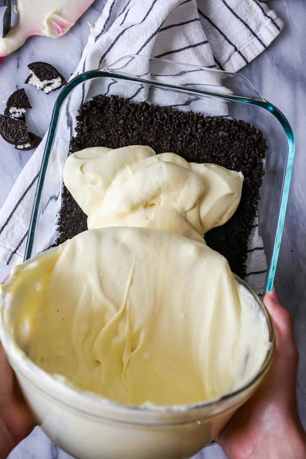Pouring pudding over oreo crust in 13x9 glass pan.