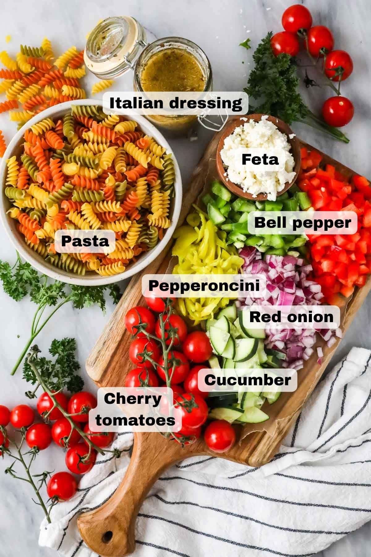 Overhead view of the ingredients needed to make pasta alad on marble and a wood board