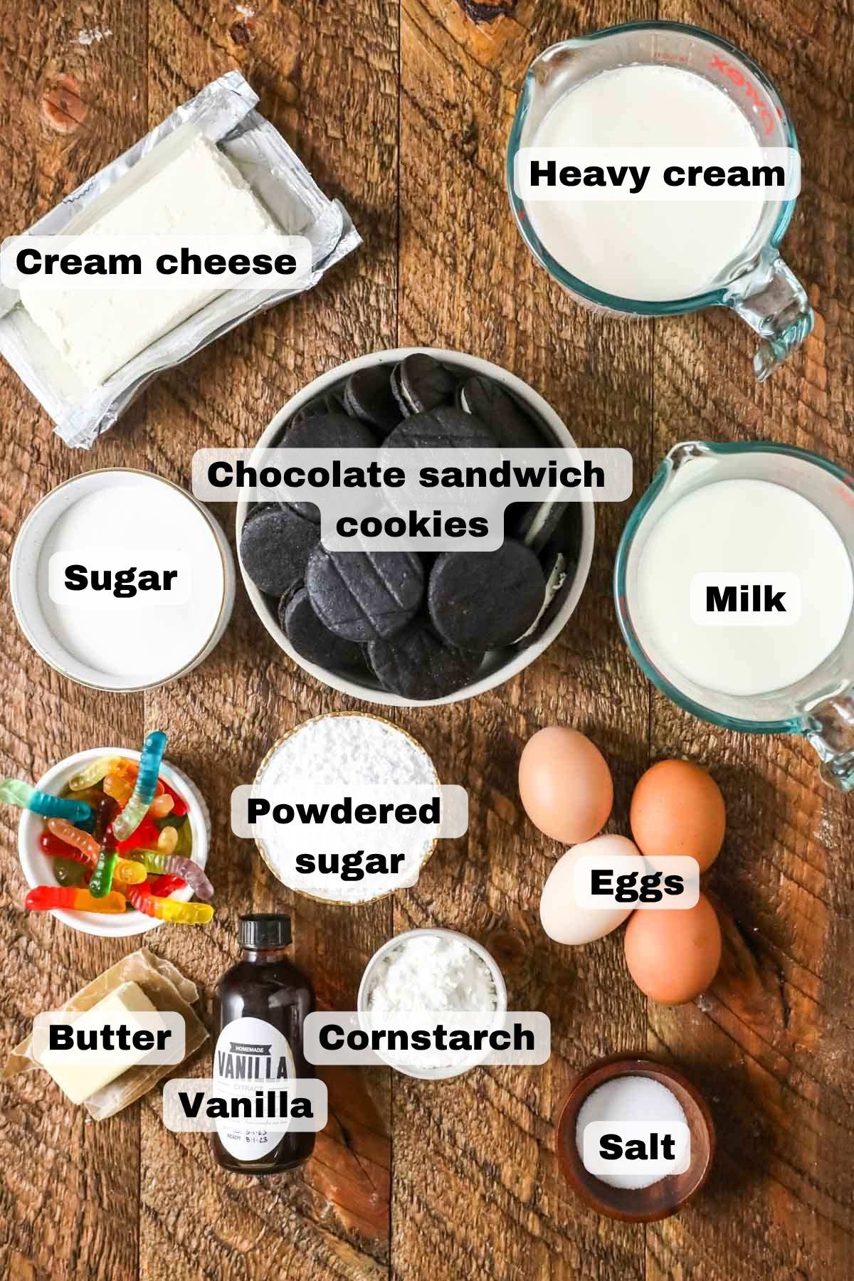 Overhead view of ingredients including chocolate cookies, cream cheese, gummy worms, and more.