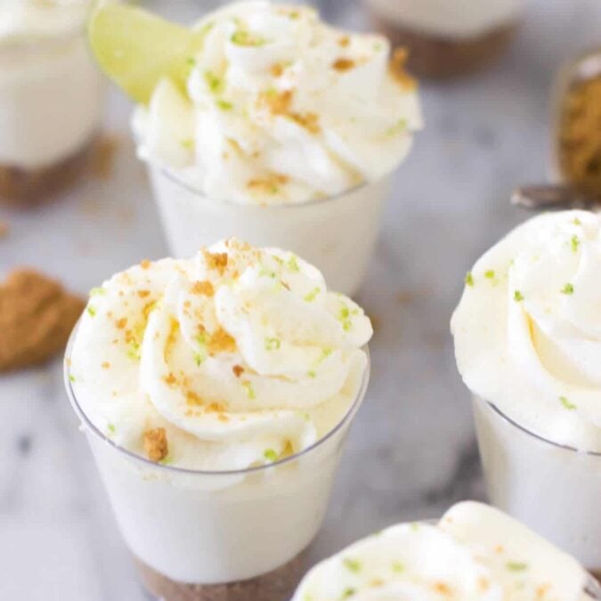 Overhead view of key lime pie dessert shooters topped with graham cracker crumbs and lime zest.