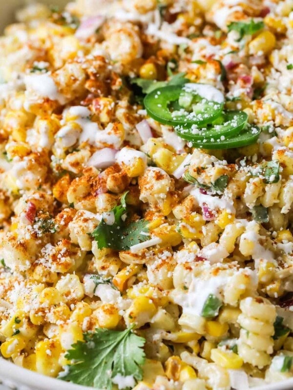 Close-up view of a Mexican street corn pasta salad topped with cilantro, jalapeno, cotija cheese, and chili powder.
