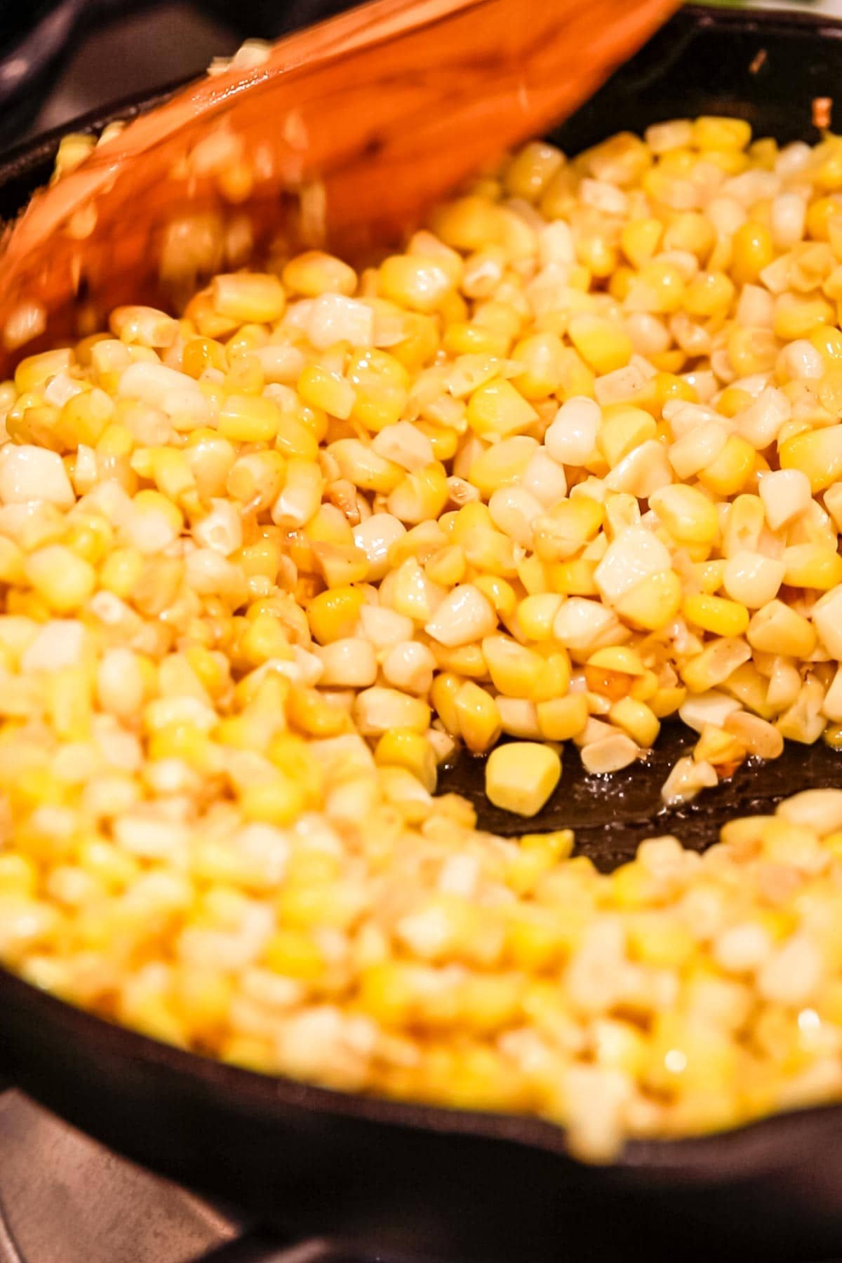 Corn kernels toasting in a cast iron pan.
