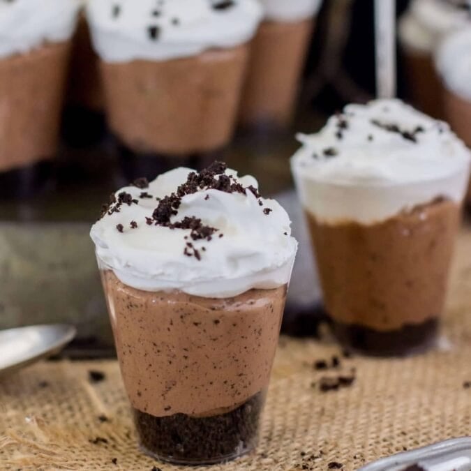 Nutella crunch dessert shooters topped with whipped cream and Oreo crumbs.