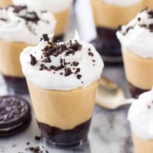 Peanut butter pie dessert shooters topped with whipped cream and Oreo crumbs.