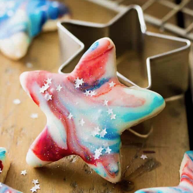 Star shaped cookie topped with a swirled red, white, and blue frosting and silver foil stars.