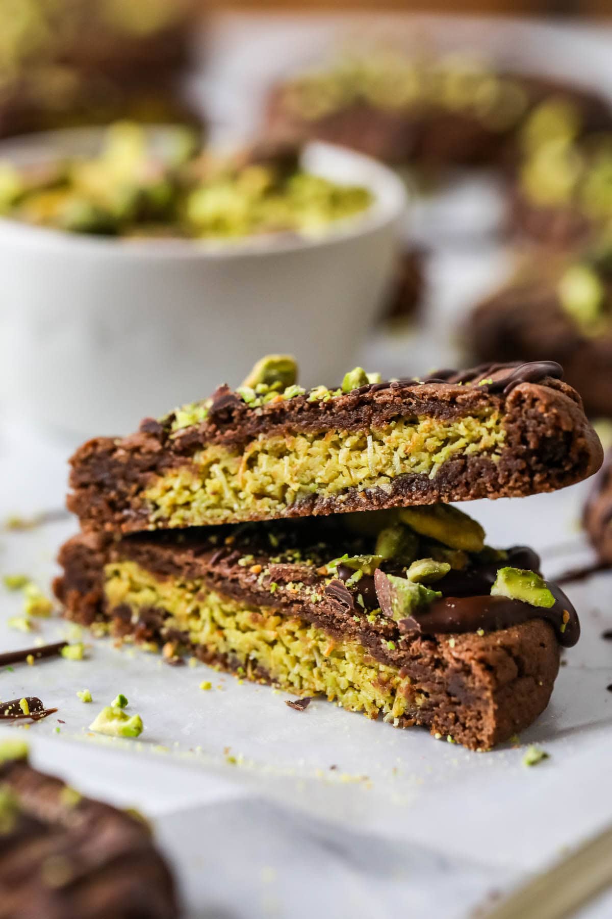 To halves of a Dubai cookie stacked on top of each other to show their pistachio filling.