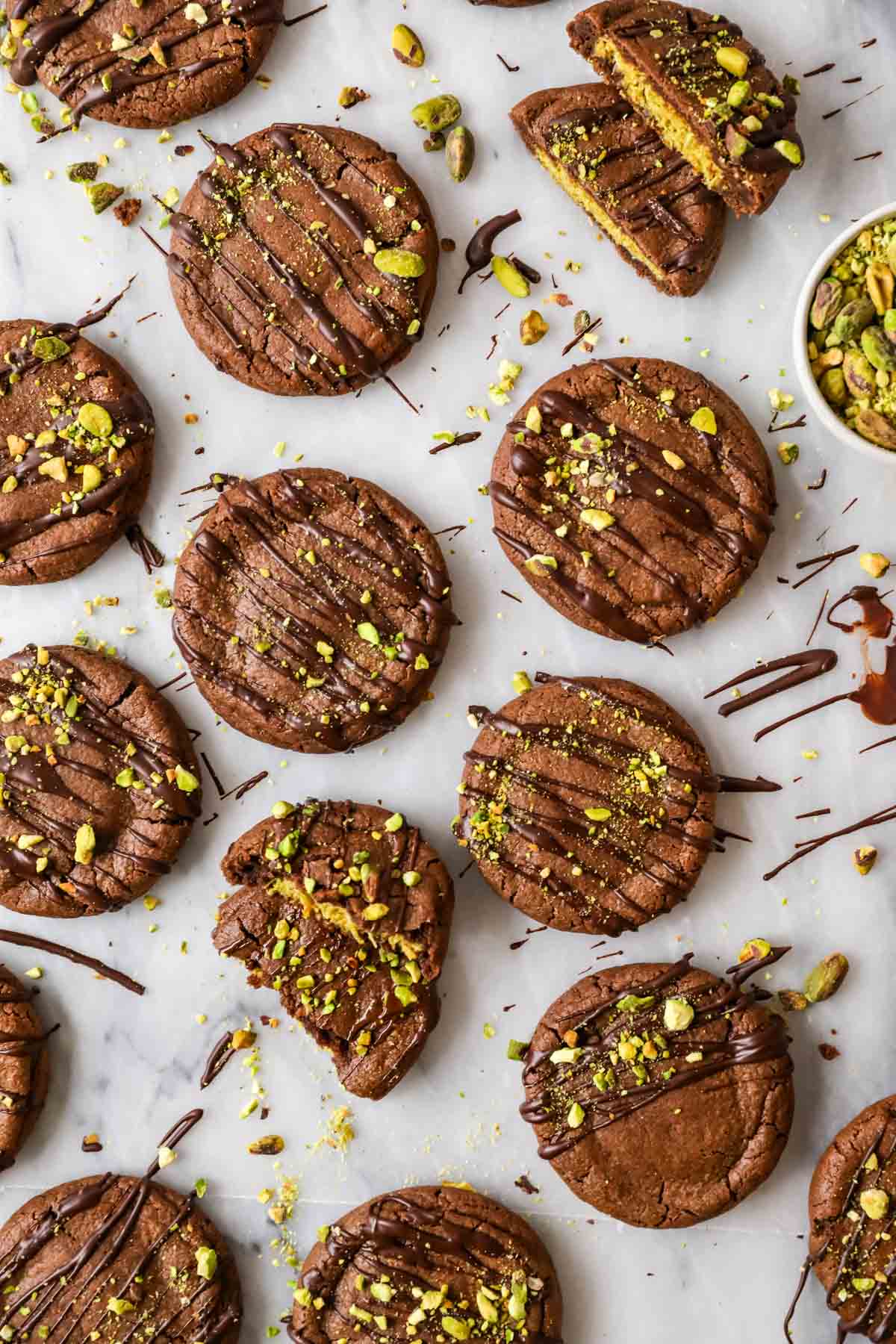 Overhead view of chocolate cookies filled with pistachio cream and topped with chopped pistachios.