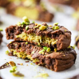 Two stacked halves of a Dubai chocolate cookie filled with pistachio cream and kataifi.