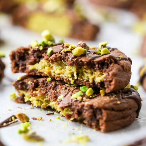 Two stacked halves of a Dubai chocolate cookie filled with pistachio cream and kataifi.