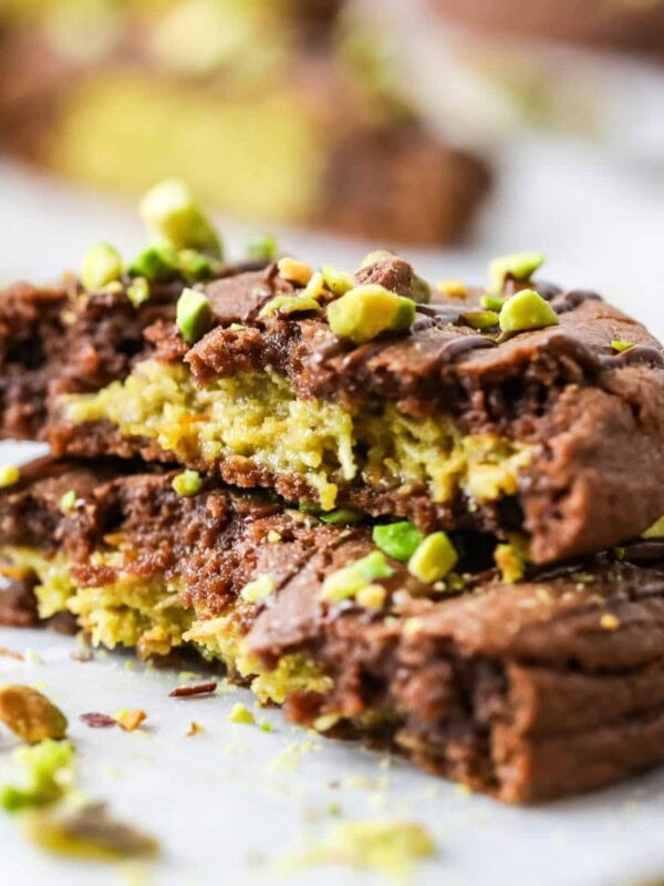 Two stacked halves of a Dubai chocolate cookie filled with pistachio cream and kataifi.