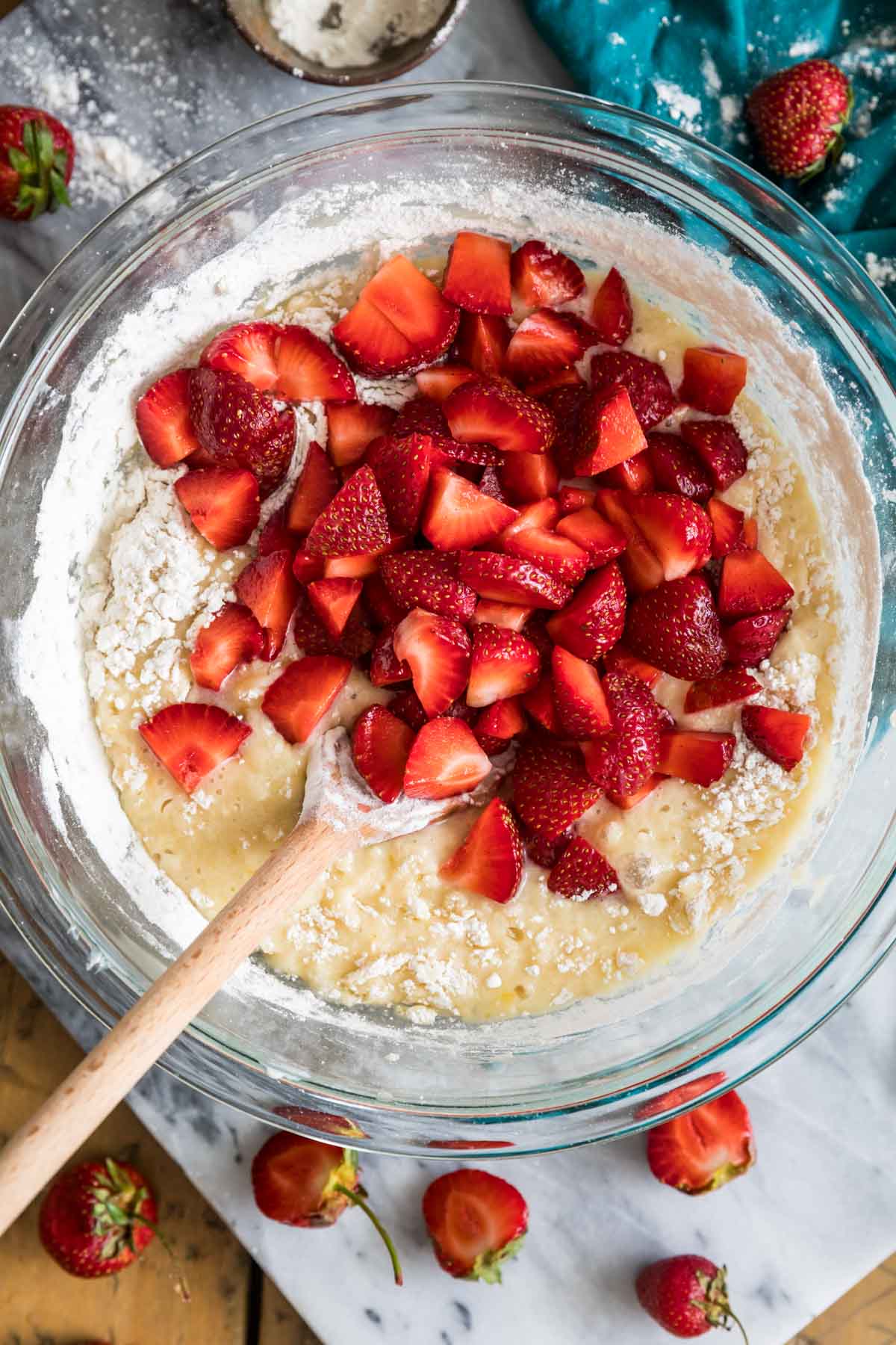 Overhead view of a bowl of muffin batter with chopped strawberries on top before folding in.
