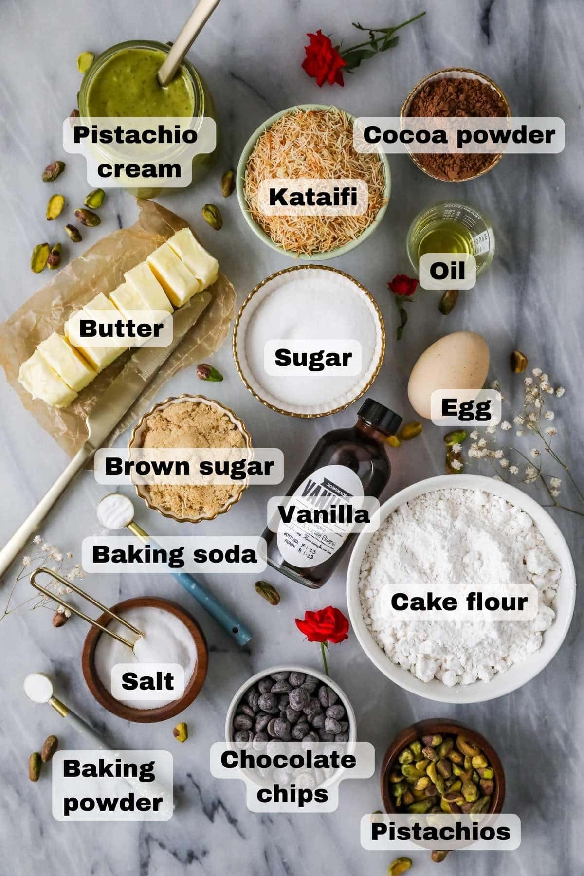 Overhead view of ingredients including pistachio cream, toasted kataifi, cocoa powder, and more.