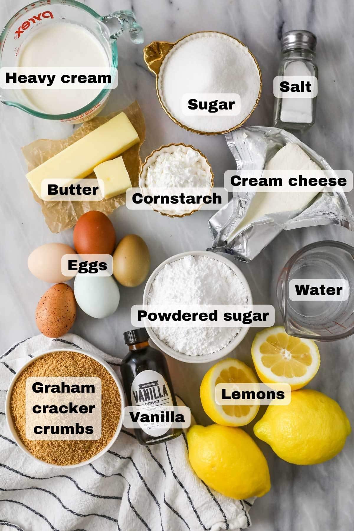 Overhead view of labeled ingredients including lemons, graham cracker crumbs, cream cheese, and more.