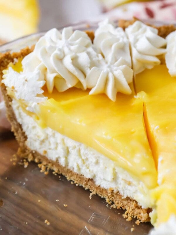 Slice of lemon cream cheese pie topped with whipped cream in a pie plate.