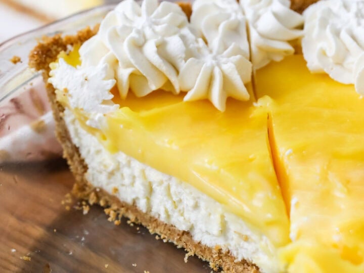 Slice of lemon cream cheese pie topped with whipped cream in a pie plate.