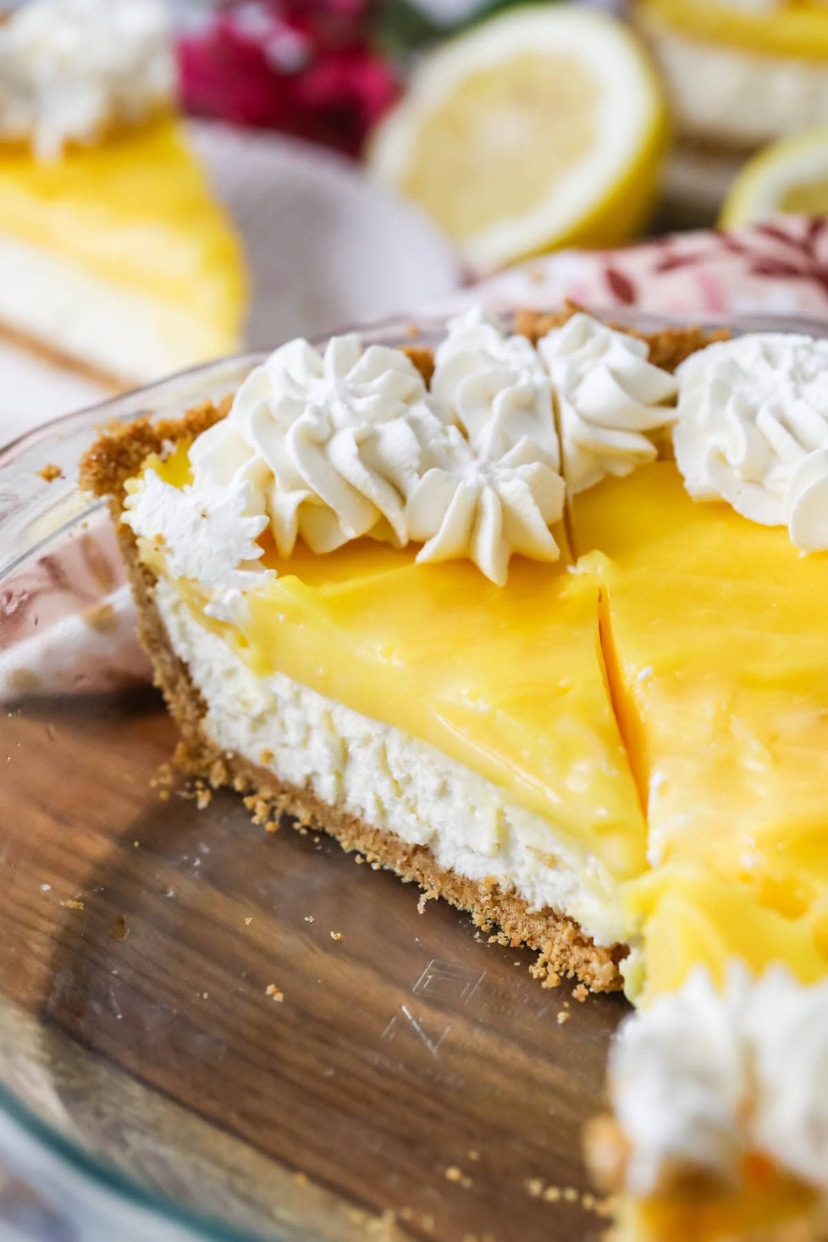 Slice of lemon cream cheese pie topped with whipped cream in a pie plate.