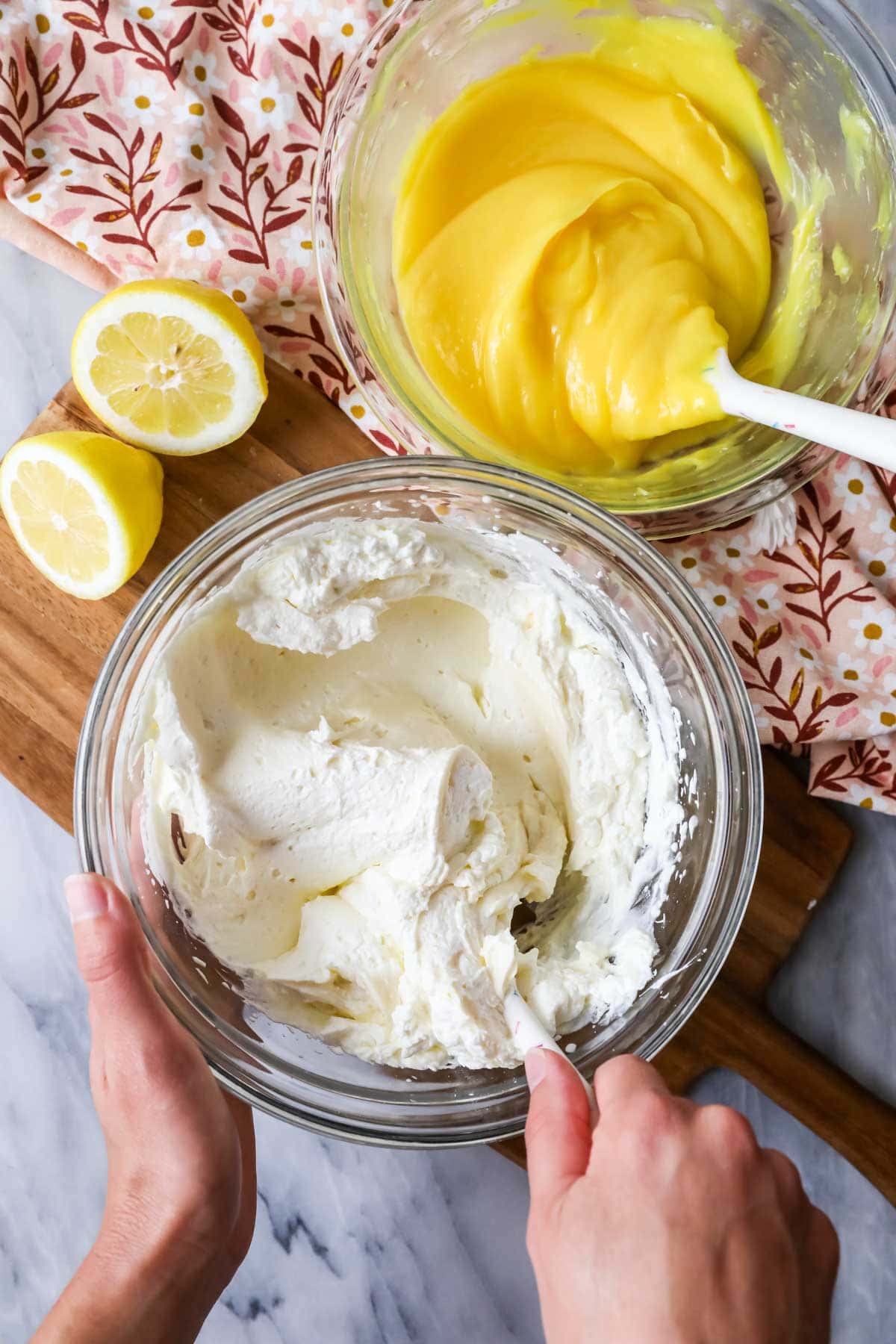 Overhead view of a whipped cream and cream cheese mixture being stirred together in a bowl.