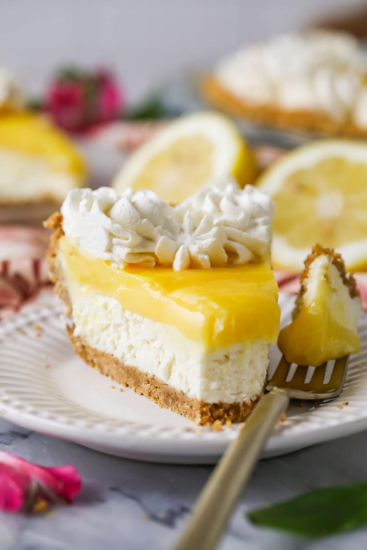 Head-on view of a slice of pie made with a graham cracker crust, cream cheese filling, and lemon topping.