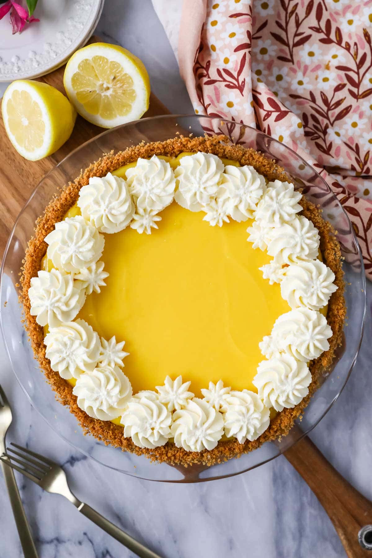 Overhead view of a pie made with a graham cracker crust, cream cheese filling, lemon topping, and whipped cream border.