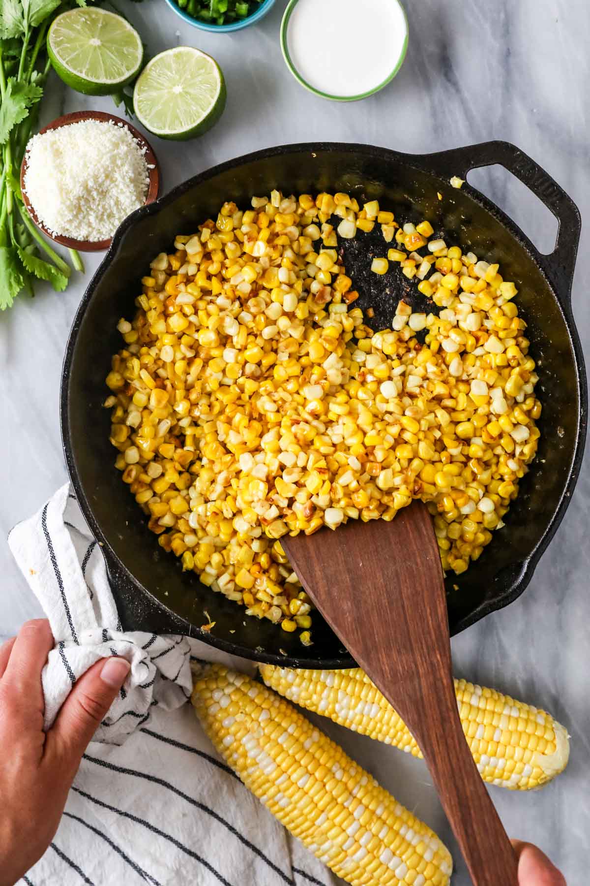 Overhead view of fresh corn being charred in a cast iron pan.