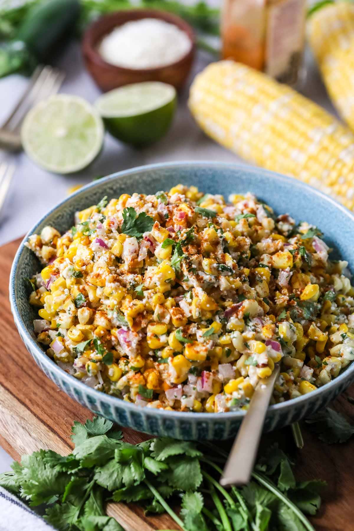 Bowl of street corn salad topped with cilantro and chili powder.