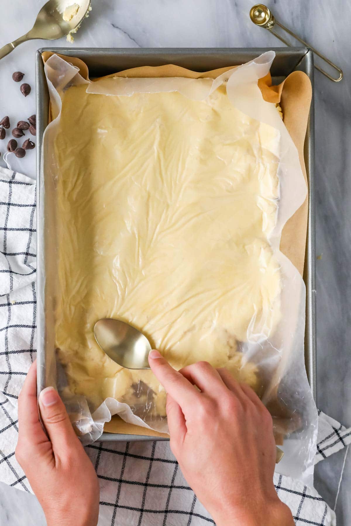 Pressing shortbread crust dough into 13x9 metal baking pan.